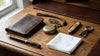 Markore Nanga Parbat bifold wallet sitting with a pocket watch and other Edwardian EDC items on a rustic surface
