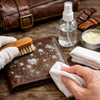 a person cleaning mold or mildew off a markore leather wallet