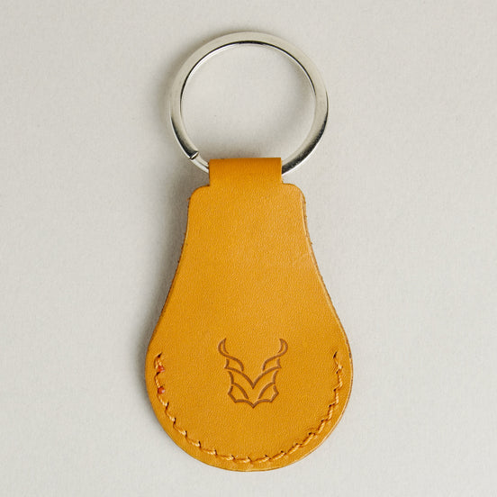 Back view of amber AirTag keychain in full-grain leather with round metal key ring and embossed logo. Markore Tag Mate.