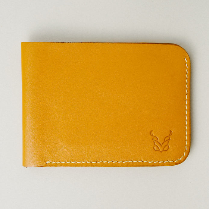 Front view of full grain leather bifold wallet in amber, featuring ivory handmade stitching and embossed logo. Markore Hunza Fold.
