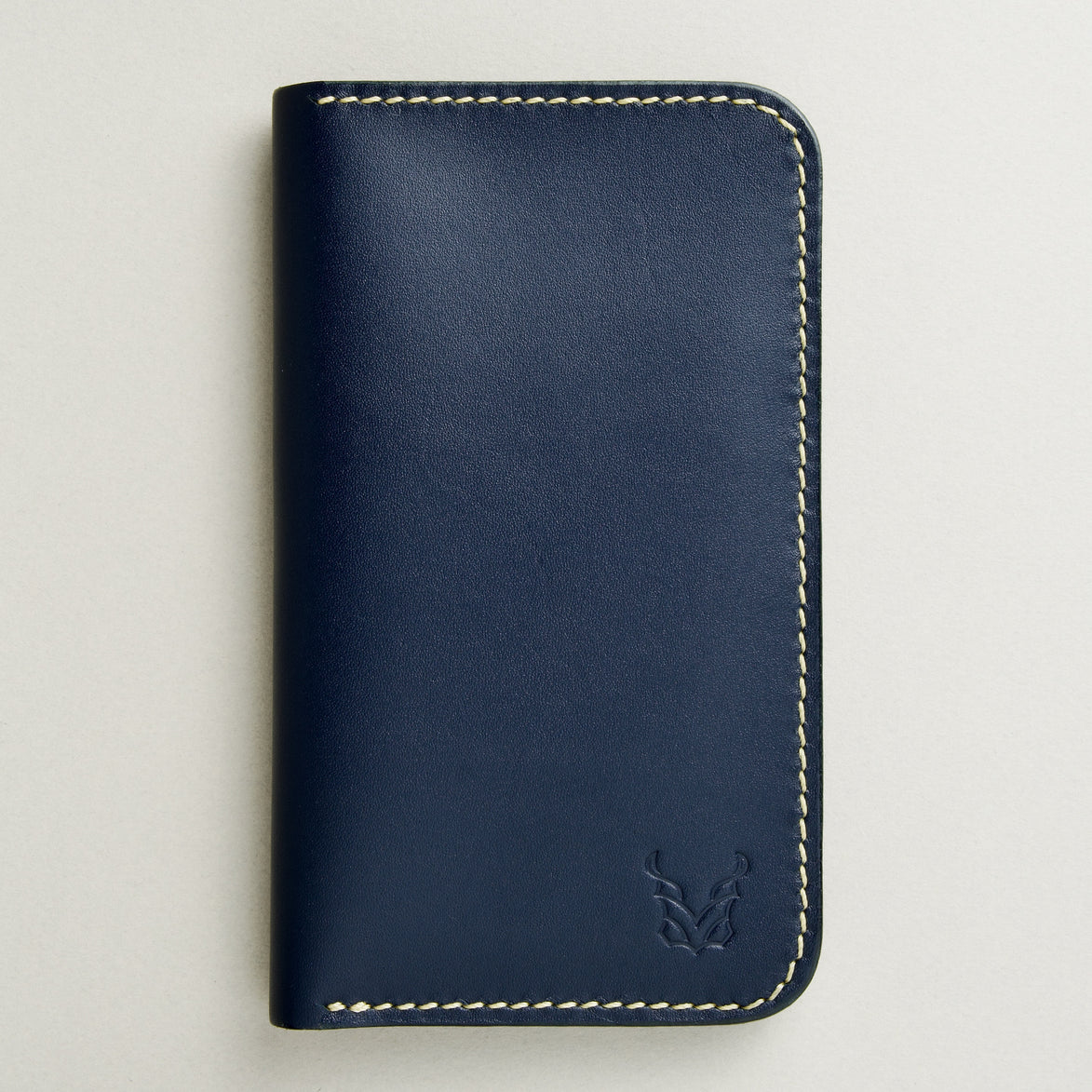 front view of vertical full-grain leather bifold wallet in dark blue, featuring handmade stitching and embossed logo. Markore Karakoram II.