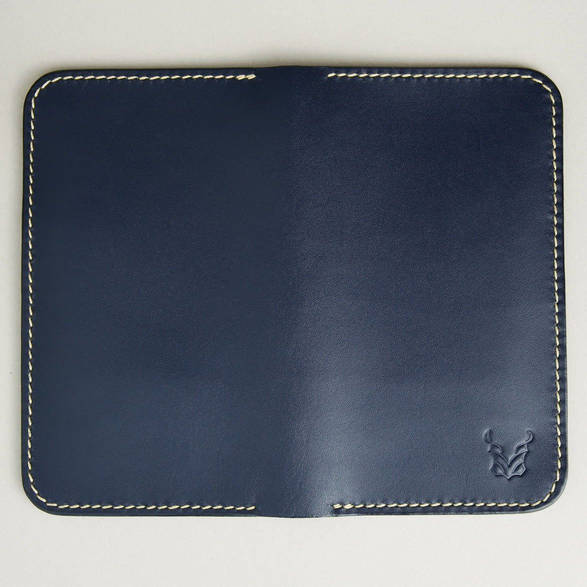 Unfolded back view of vertical full-grain leather bifold wallet in Dark Blue, featuring handmade stitching and embossed logo. Markore Karakoram II.
