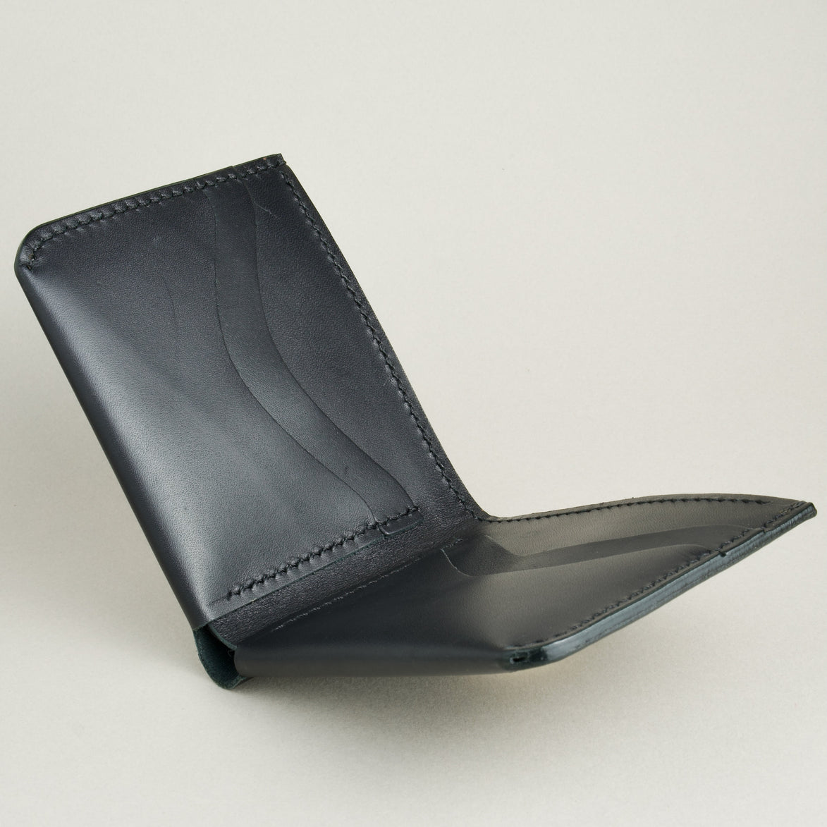 Side view of midnight black full-grain leather wallet featuring a seamless bottom edge, card slots adndhandmade stitching. Markore Assam Silk.