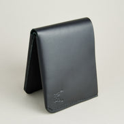 Side view of midnight black full-grain leather wallet featuring a seamless bottom edge, handmade stitching and embossed logo. Markore Assam Silk.