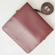 Unfolded outside view of horizontal full-grain leather crossbody bag and matching shoulder strap in Espresso Brown, showing handmade stitching and embossed logo. Markore Gul Sahar.