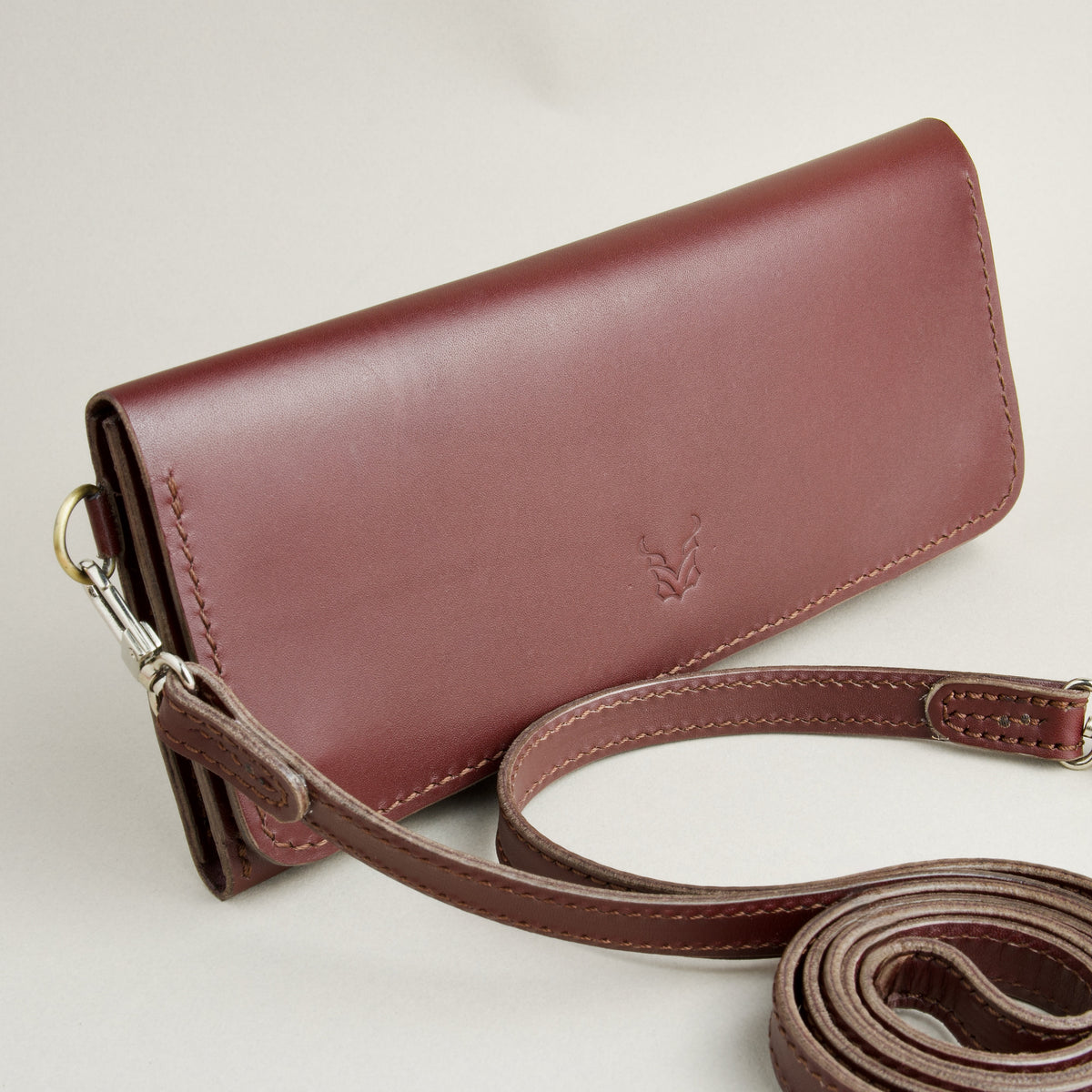 Side view of horizontal full-grain leather crossbody bag and matching shoulder strap in Espresso Brown, showing handmade stitching and embossed logo. Markore Gul Sahar.