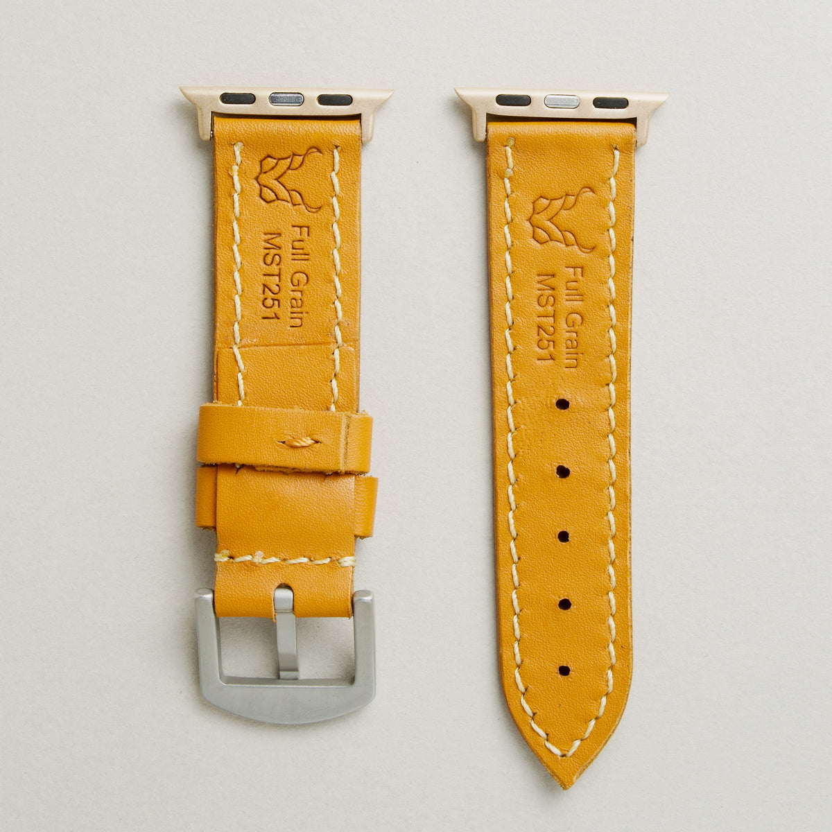 Back view of amber leather strap with rose gold stainless steel adapters and silver buckle, showing handmade stitching, embossed logo, and serial number. Markore Hour Line.