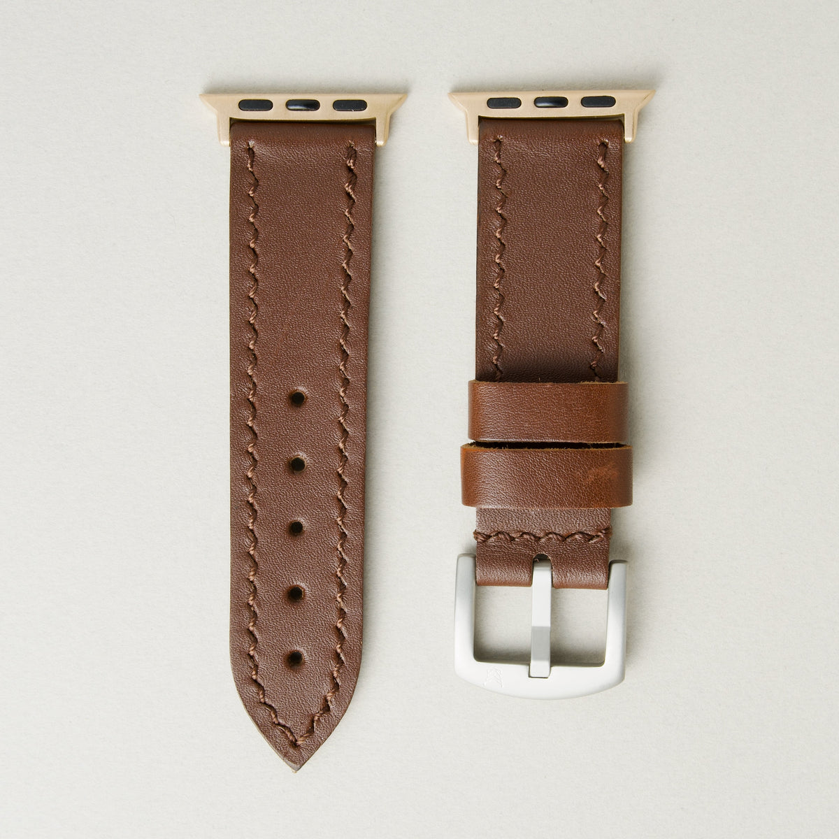 Espresso brown full-grain leather watch strap with rose gold stainless steel adapters and silver buckle, featuring handmade stitching and matching loops. Markore Hour Line.
