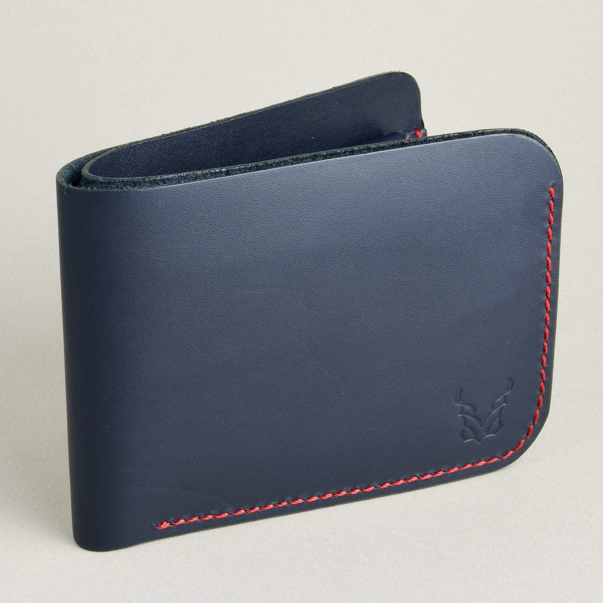 side view of vegetable tanned leather bifold wallet with hand-stitched red thread in Dark Blue. Markore Hunza Arc.
