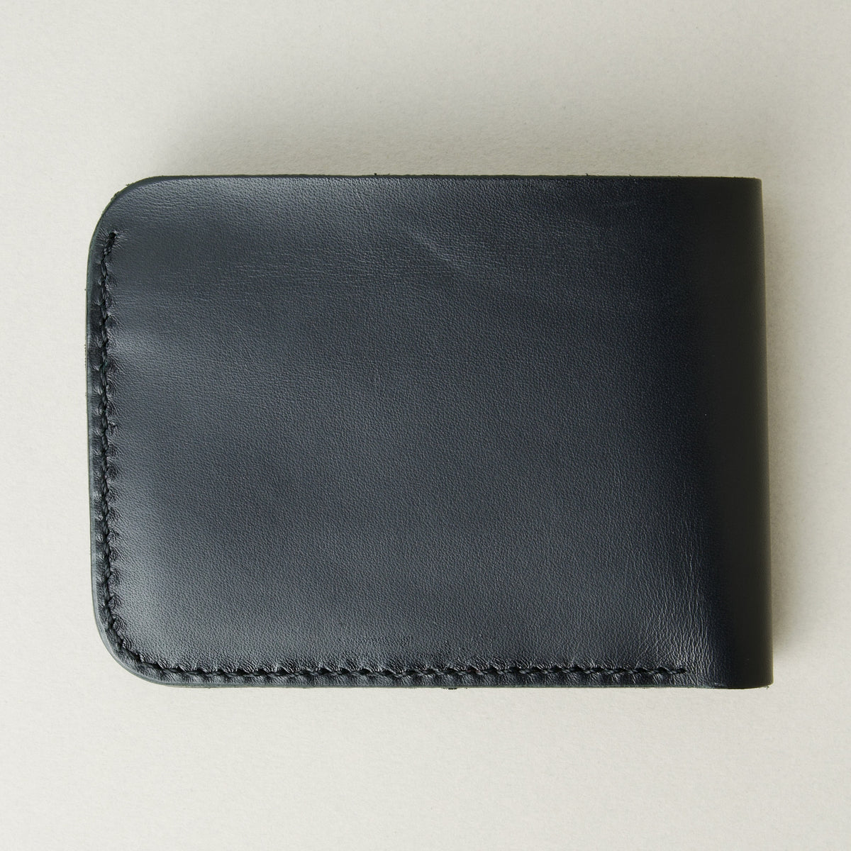 Back view of full grain leather bifold wallet in midnight black featuring handmade stitching. Markore Hunza Fold.
