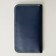 Back view of vertical full-grain leather bifold wallet in dark blue, featuring handmade stitching in ivory. Markore Karakoram II.