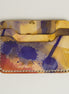 Backside view of hand-painted full-grain leather card sleeve in purple, amber, and brown, featuring handmade stitching. Markore Niva Chaos.