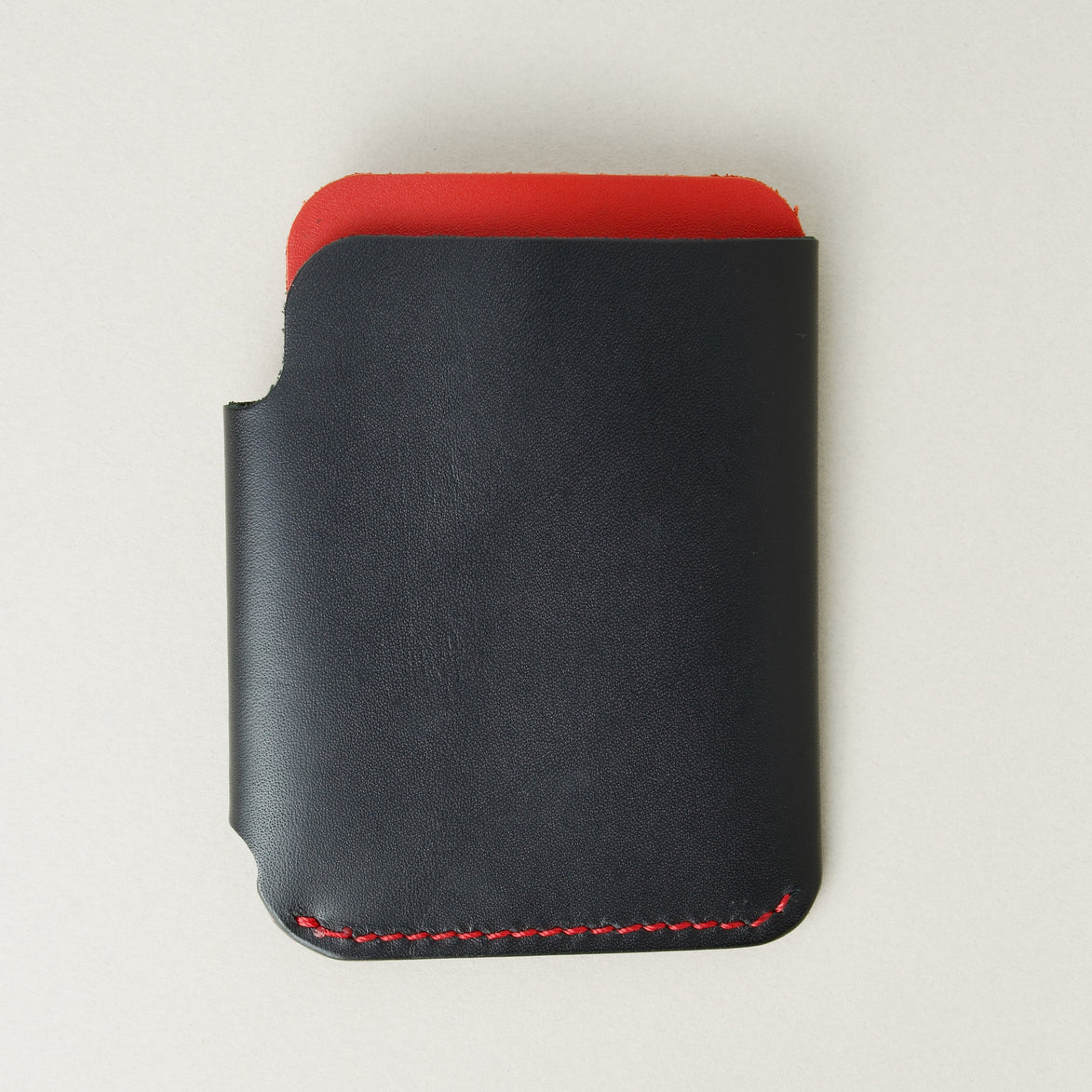 Back view of full grain leather card holder in black and red, featuring red handmade stitching. Markore Niva Glide.