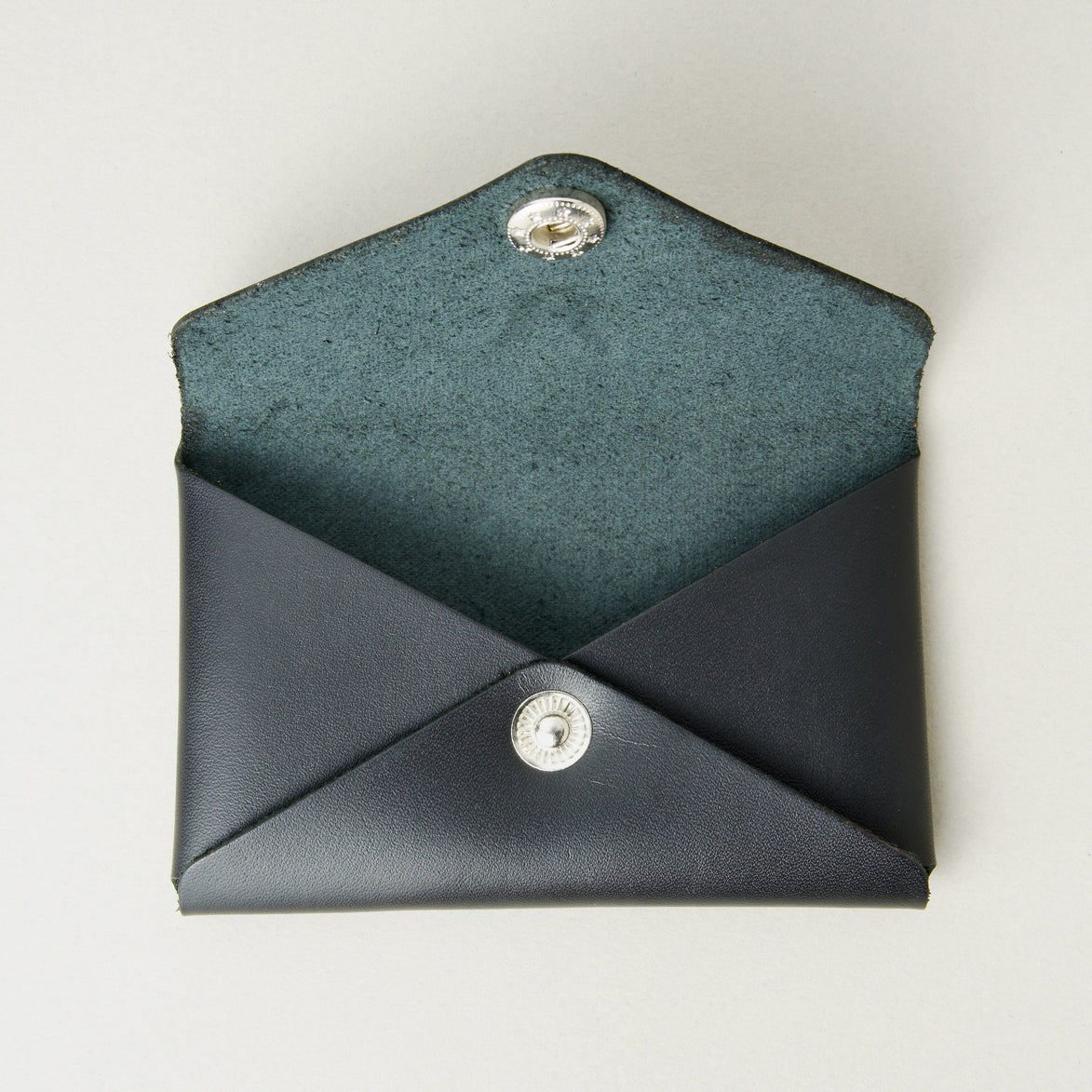 Front view of full grain leather envelope style wallet with open flap in midnight black with stainless steal press button. Markore Niva Seal.
