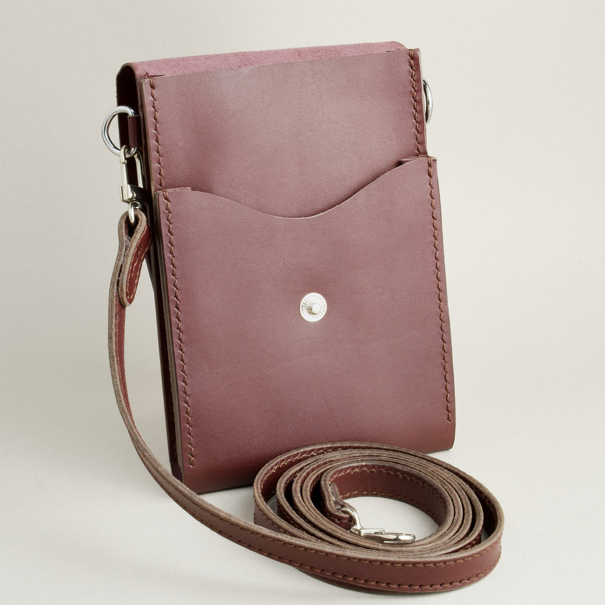 Inside view of vertical full-grain leather crossbody bag and matching shoulder strap in Espresso Brown, showing handmade stitching and stainless steel press stud. Markore Nora Veldt.