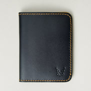 Front view of midnight black full-grain leather wallet featuring amber handmade stitching and embossed logo. Markore Ravi Fold.