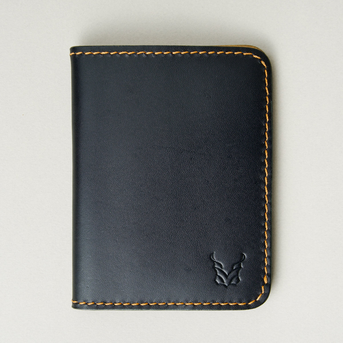 Front view of midnight black full-grain leather wallet featuring amber handmade stitching and embossed logo. Markore Ravi Fold.