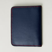 Back view of dark blue full-grain leather wallet featuring red handmade stitching. Markore Ravi Fold.