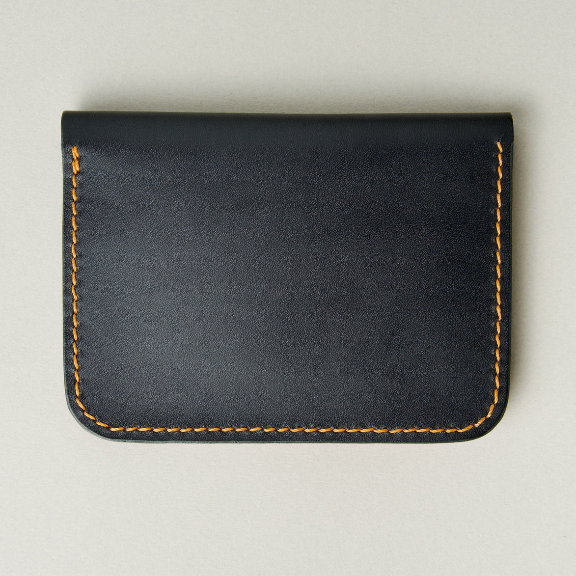 Back view of midnicht black full-grain leather wallet featuring amber handmade stitching. Markore Ravi Slip.