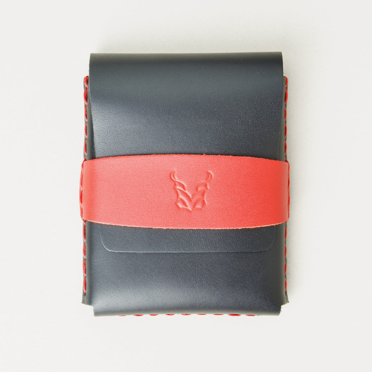 Front view of midnight black full-grain leather flap wallet featuring a red flap holder with embossed logo, and red handmade stitching. Markore Sutlej Vault.