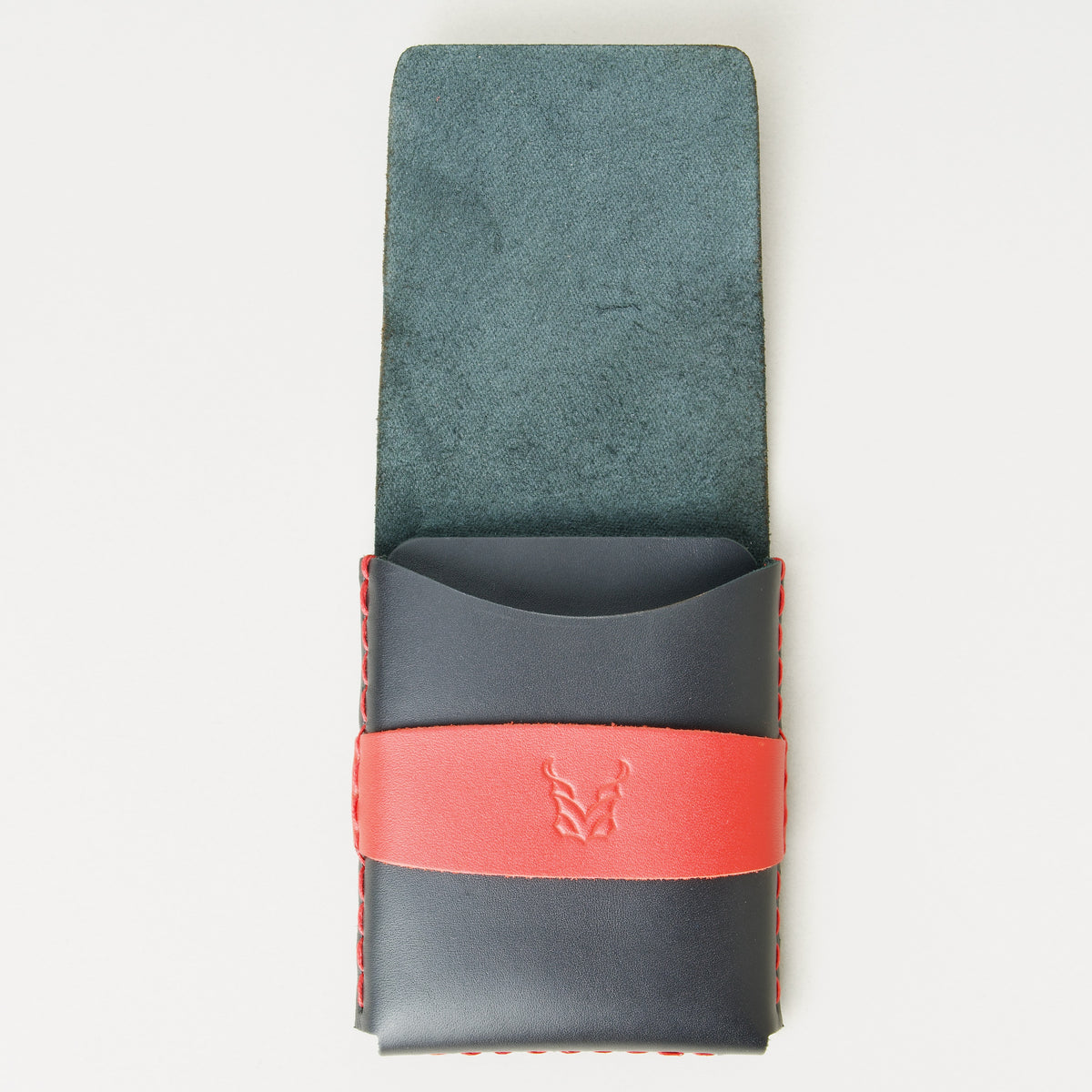 Front view of midnight black full-grain leather flap wallet with open flap, featuring a red flap holder with embossed logo, and red handmade stitching. Markore Sutlej Vault.