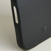 Detail of midnight black leather iphone 17 pro case featuring button cutout and embossed logo. Markore Shell Frame.