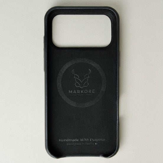Inside view of midnight black leather iphone 17 pro case with full cutout showing velvet lining and brand logo. Markore Shell Frame.