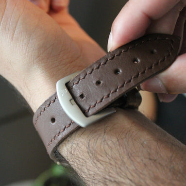 Person adjusting a brown leather markore hour line apple watch strap