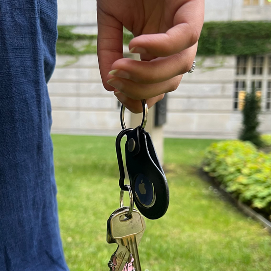 Hand holding keys with a blurred background of grass and a building